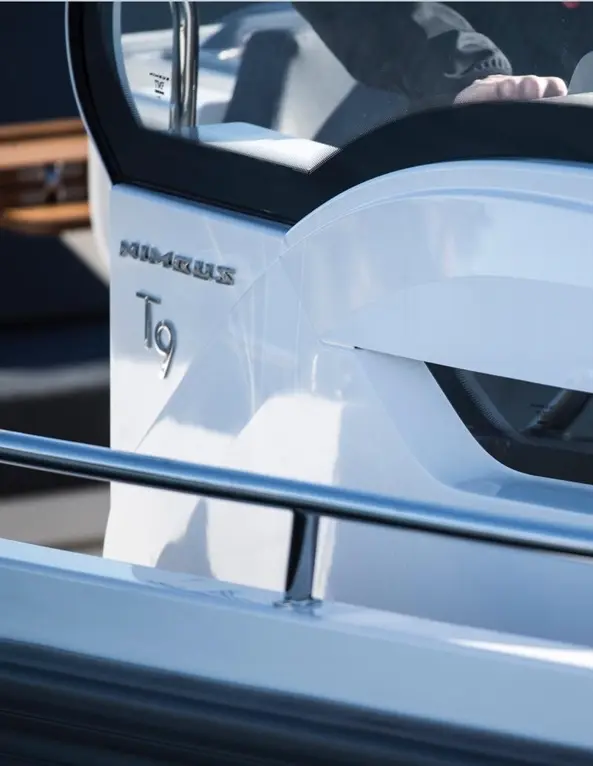 Close-up of a Nimbus T9 boat's sleek dashboard, featuring a clear windshield and polished railings, highlighting modern design.